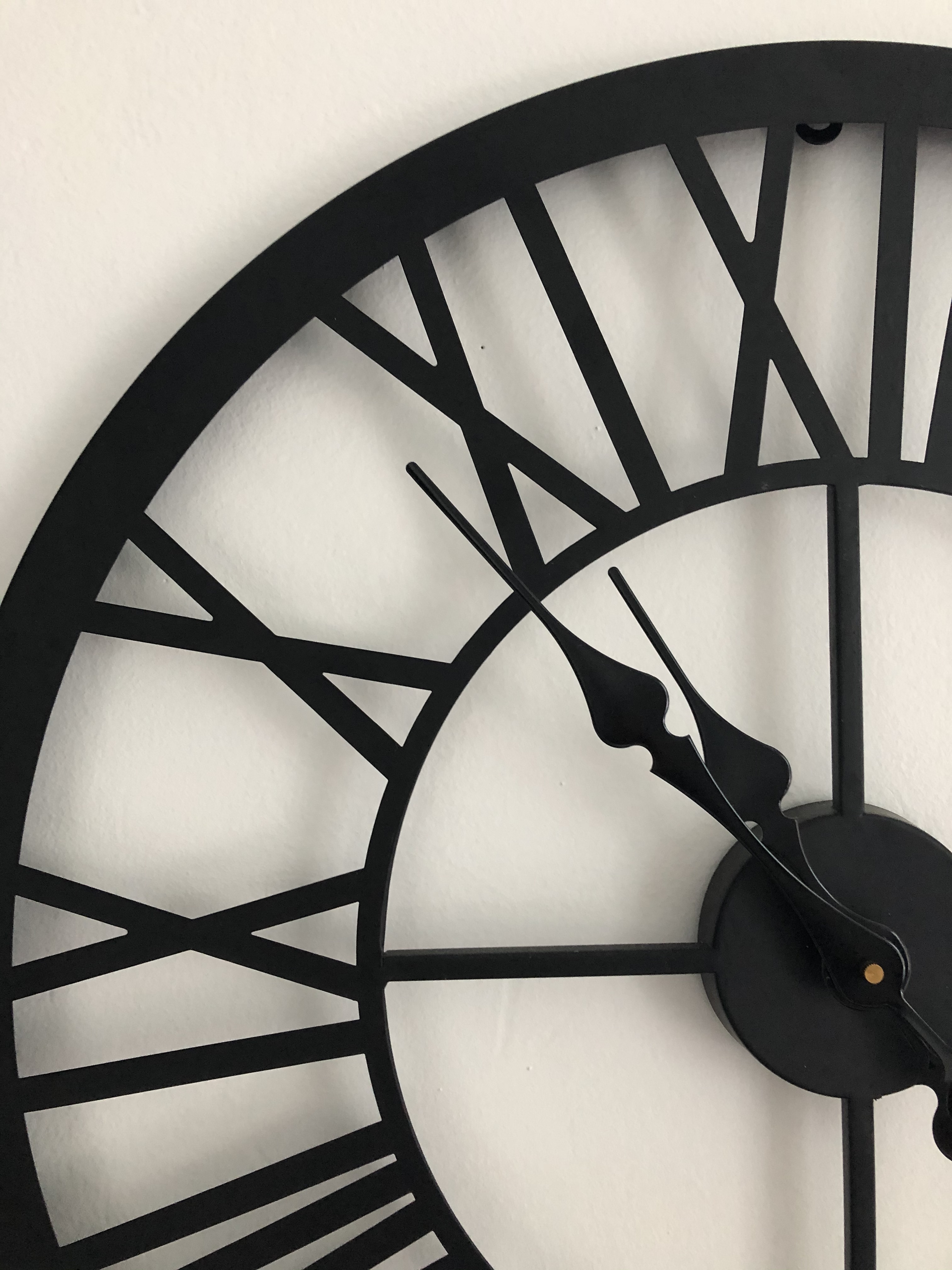 Wall clock with black face on a white wall.
