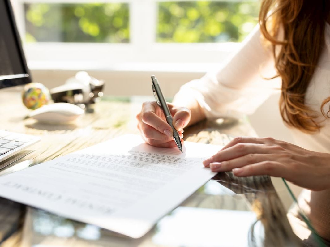 Person writing on paper at a desk Person writing on a piece of paper at a desk